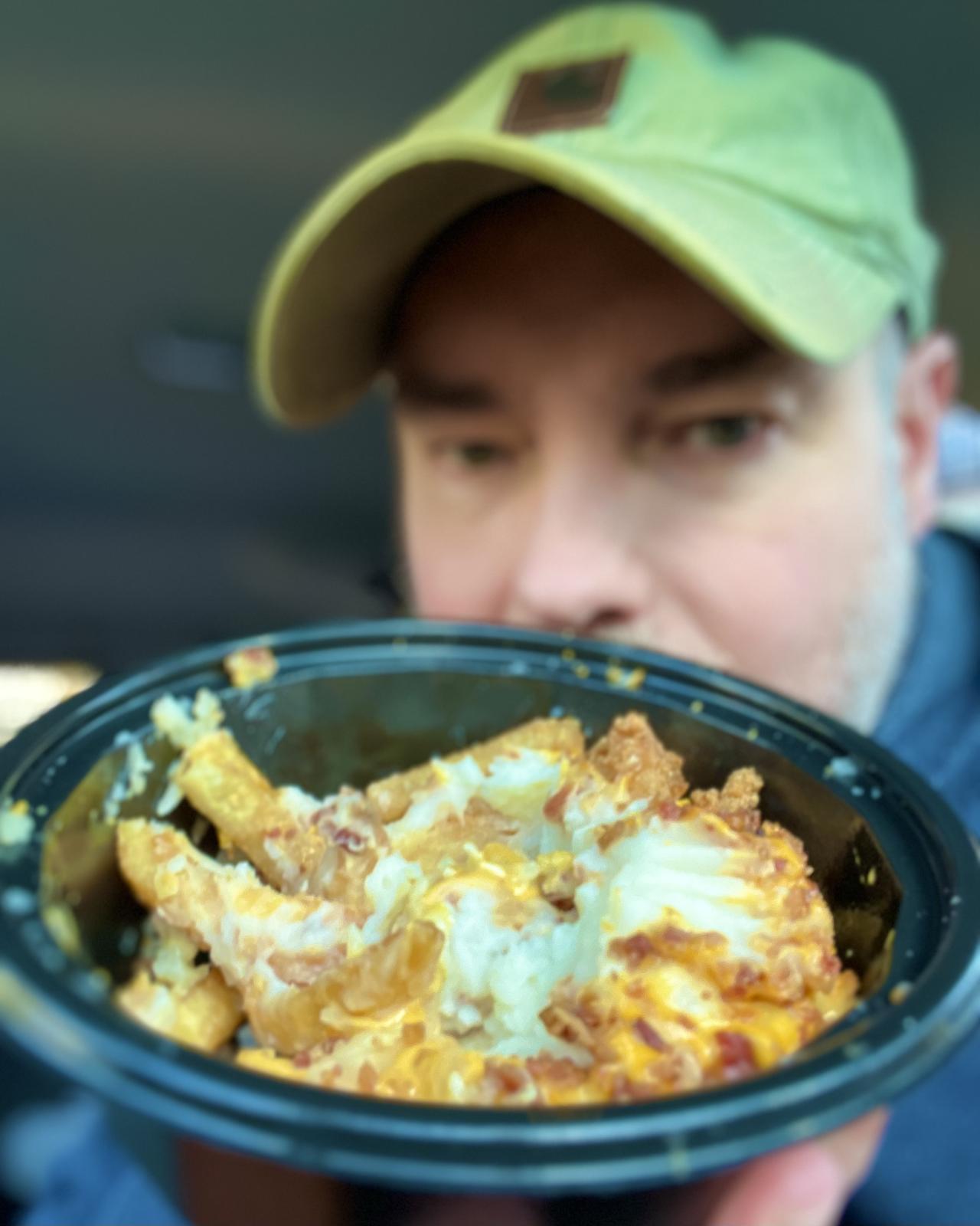 Matt Calkins behind a half-eaten Kentucky Fried Chicken (KFC) Smash'd Potato Bowl With Nuggets.